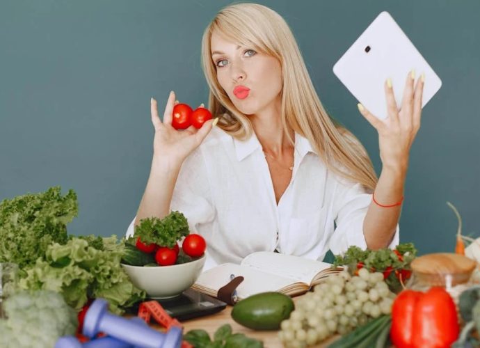 Vlogger promoting healthy eating with fresh vegetables on the table.