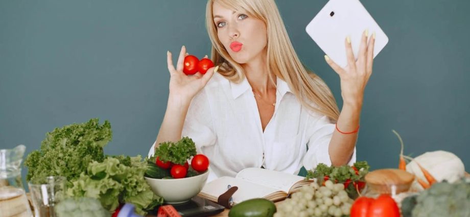 Vlogger promoting healthy eating with fresh vegetables on the table.